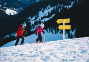 Skier walking on snow with a child, sharing a joyful moment in a winter wonderland