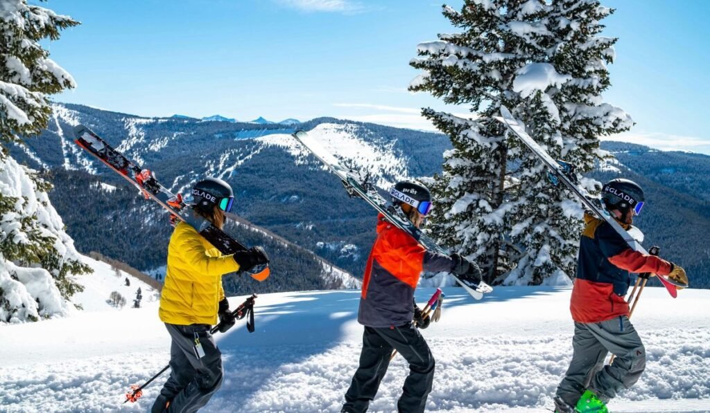 Three men carrying skis on their shoulders, ready for maintenance in a snowy setting