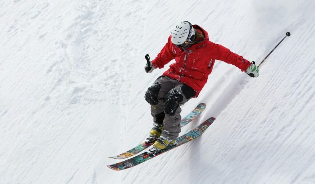 Man in red jacket skiing on snowy slopes during the day